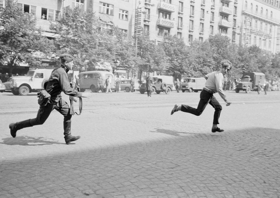 the prague spring of 1968: soviet soldier chasing young man who had thrown stones at a tank