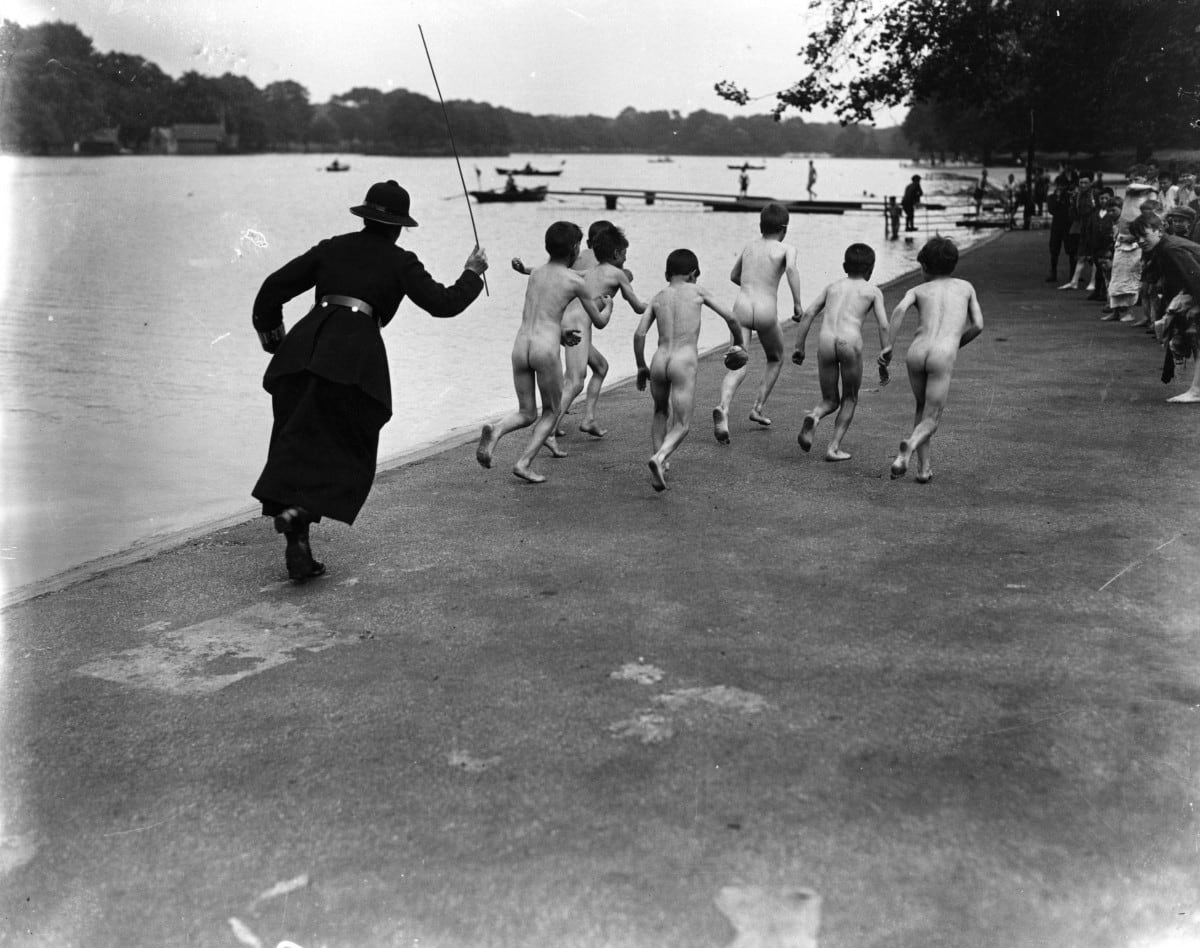 a gang of skinny dippers is chased down the street at hyde park by a police woman, 1926