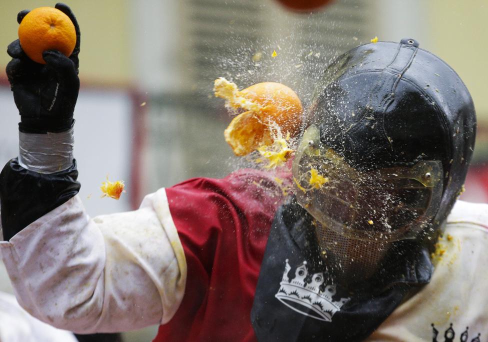 A member of a rival team is hit by an orange during an annual carnival battle in the northern Italian town of Ivrea