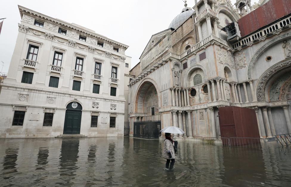 a woman walks through the flooded st. mark's square during a period of seasonal high water and on the first day of carnival, in venice
