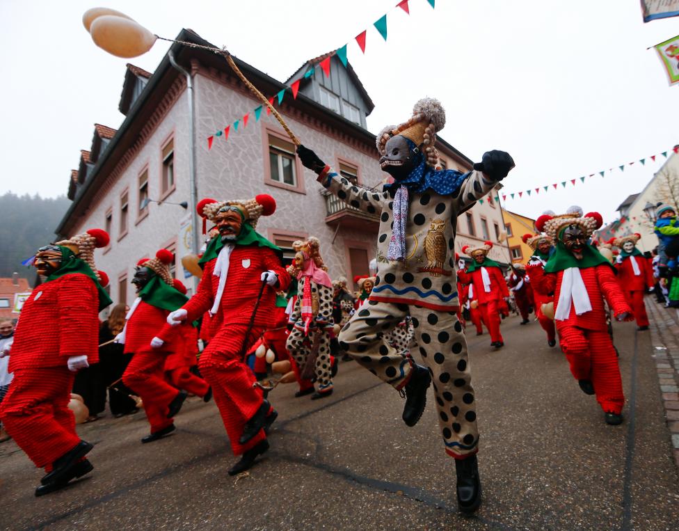 revellers in traditional costumes and carnival masks parade through the village of elzach in the black forest