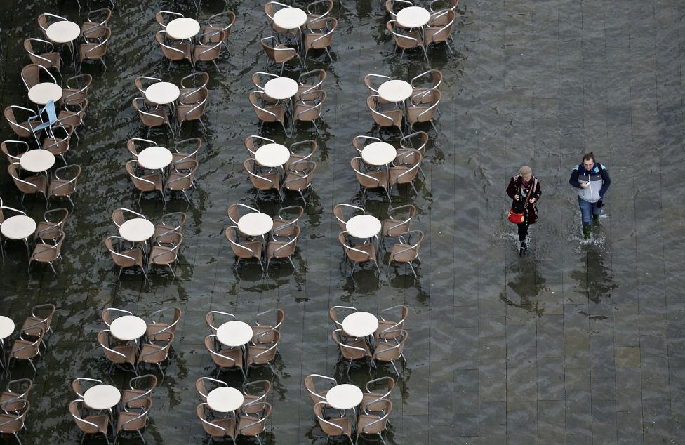 people walk on the flooded st. mark's square during a period of seasonal high water and on the first day of carnival, in venice