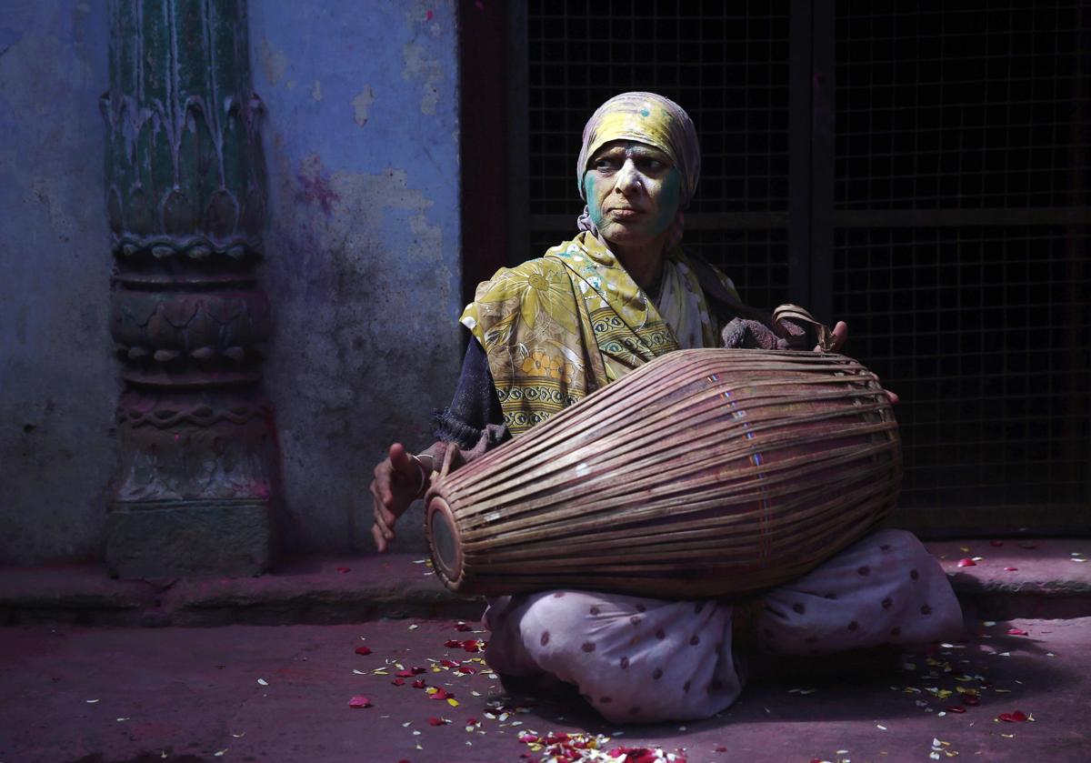 A widow daubed in colors played a drum at a widows' ashram at Vrindavan on March 6. (Ahmad Masood/Reuters)