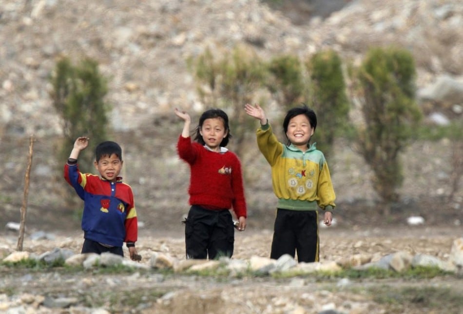 North Korean children wave to people on a Chinese tourist boat on the banks of Yalu River near the Chongsong county of North Korea, opposite the Chinese border city of Dandong, May 8, 2011. (Photo by Jacky Chen/Reuters)