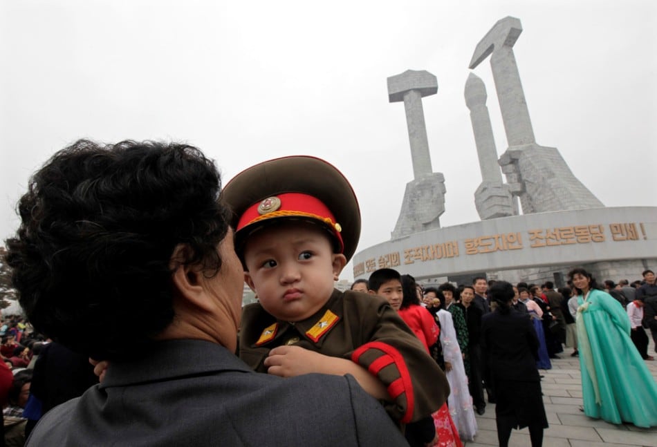 A woman carries a boy dressed in a North Korean army uniform at the Party Foundation Monument in Pyongyang October 11, 2010. (Photo by Petar Kujundzic/Reuters)