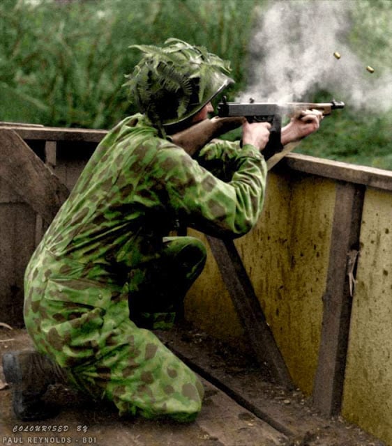 A US Marine wearing his camouflage suit fires a Thompson sub-machine gun during Jungle Training - 1942. (Colorized by Paul Reynolds. Historic Military Photo Colourisations)