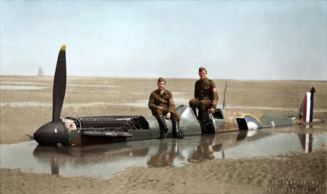 Two German members of the Organisation Todt (involved in the construction of the Atlantic Wall) are sitting on the Spitfire brought down on the wet sands at Calais by Flying Officer Peter Cazenove. It had been hit by a single bullet from a German Dornier bomber. The plane was consumed by the sandy beach and remained there for 40 years. (Colorized by Paul Reynolds. Historic Military Photo Colourisations)