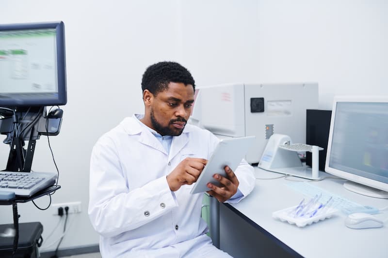 black medical scientist analyzing data on tablet D7XFWEP