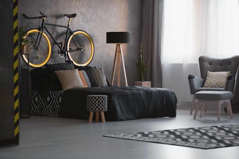 bike above black bed in dark bedroom interior D6SAGH7