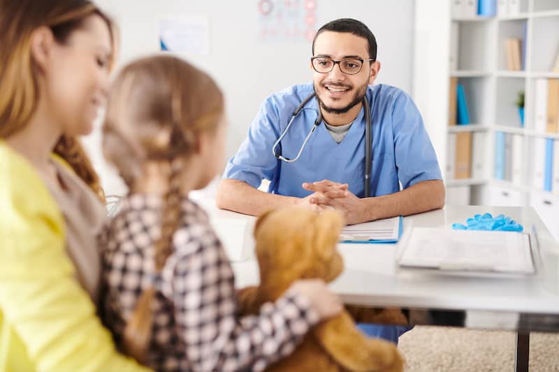 smiling pediatrician talking to child R7JC5YT
