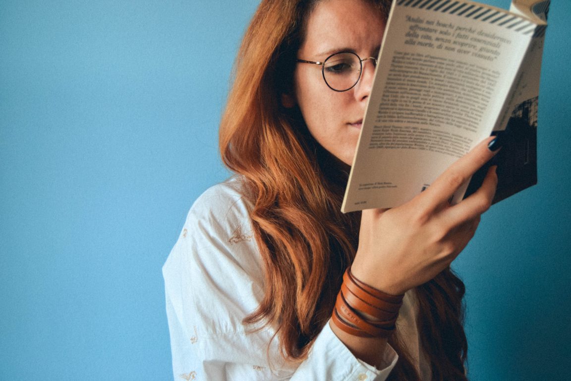 woman wearing eyeglasses holding a book