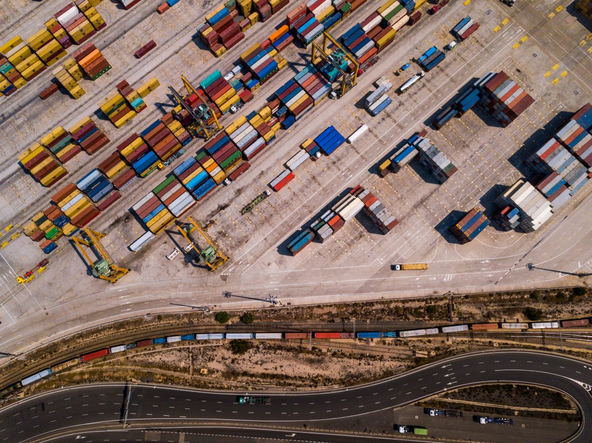 industrial cargo area with container ship in dock at port, aerial view of transport pier.