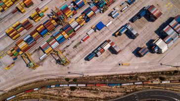 industrial cargo area with container ship in dock at port, aerial view of transport pier.