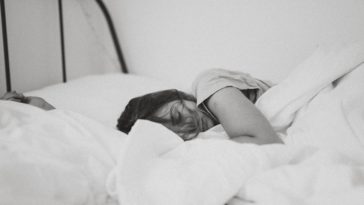 grayscale photo of sleeping woman lying on bed
