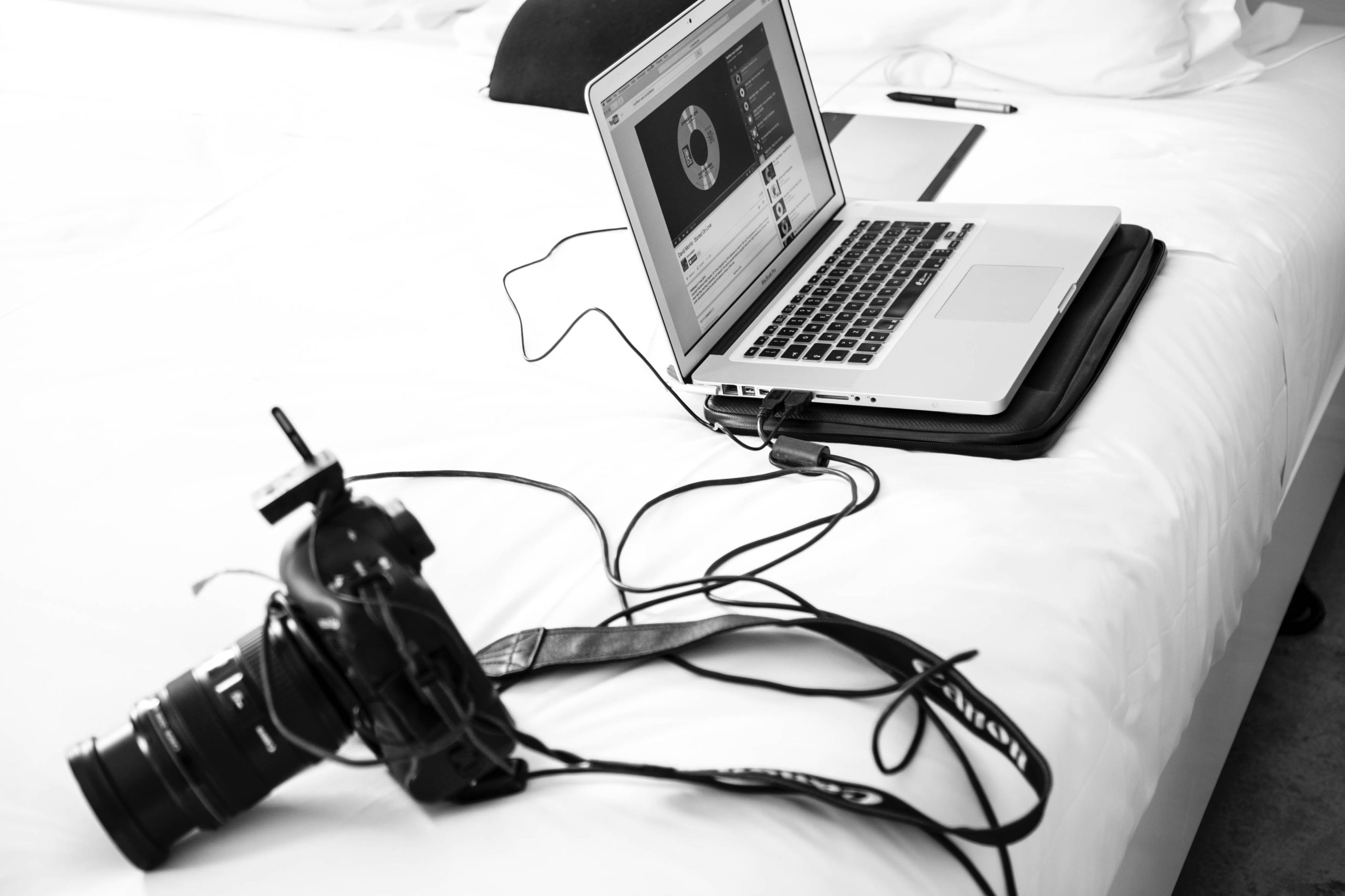 grayscale photography of DSLR camera and MacBook Pro