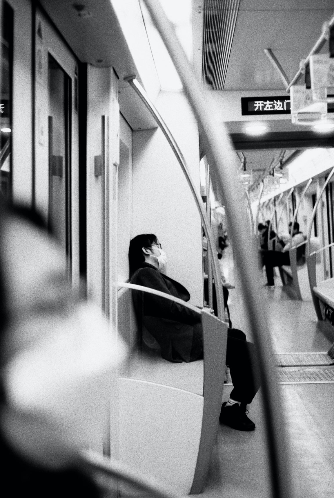 grayscale photo of woman in black jacket sitting on train