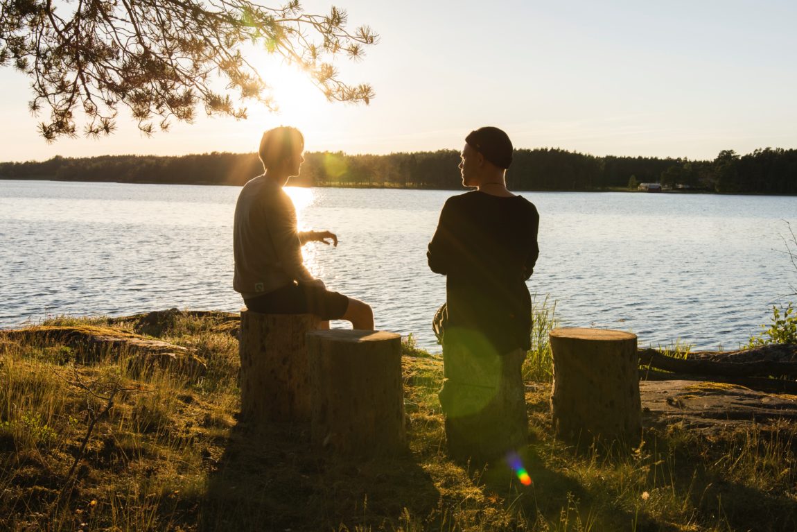 Conversation man in black jacket standing beside body of water during sunset