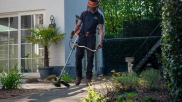 man in black t-shirt and blue denim jeans holding shovel