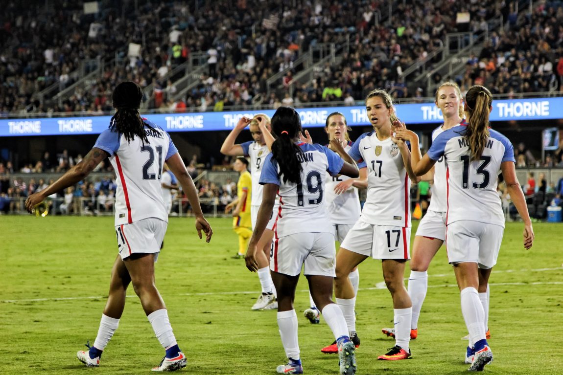 Football team female soccer players at the field near people on bleachers
