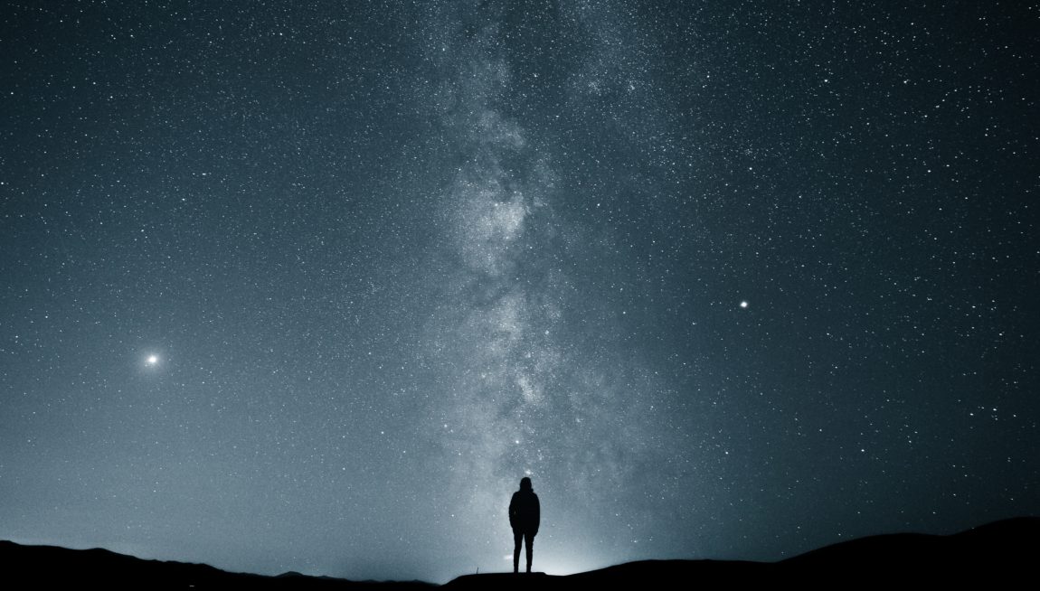 silhouette of person under starry sky