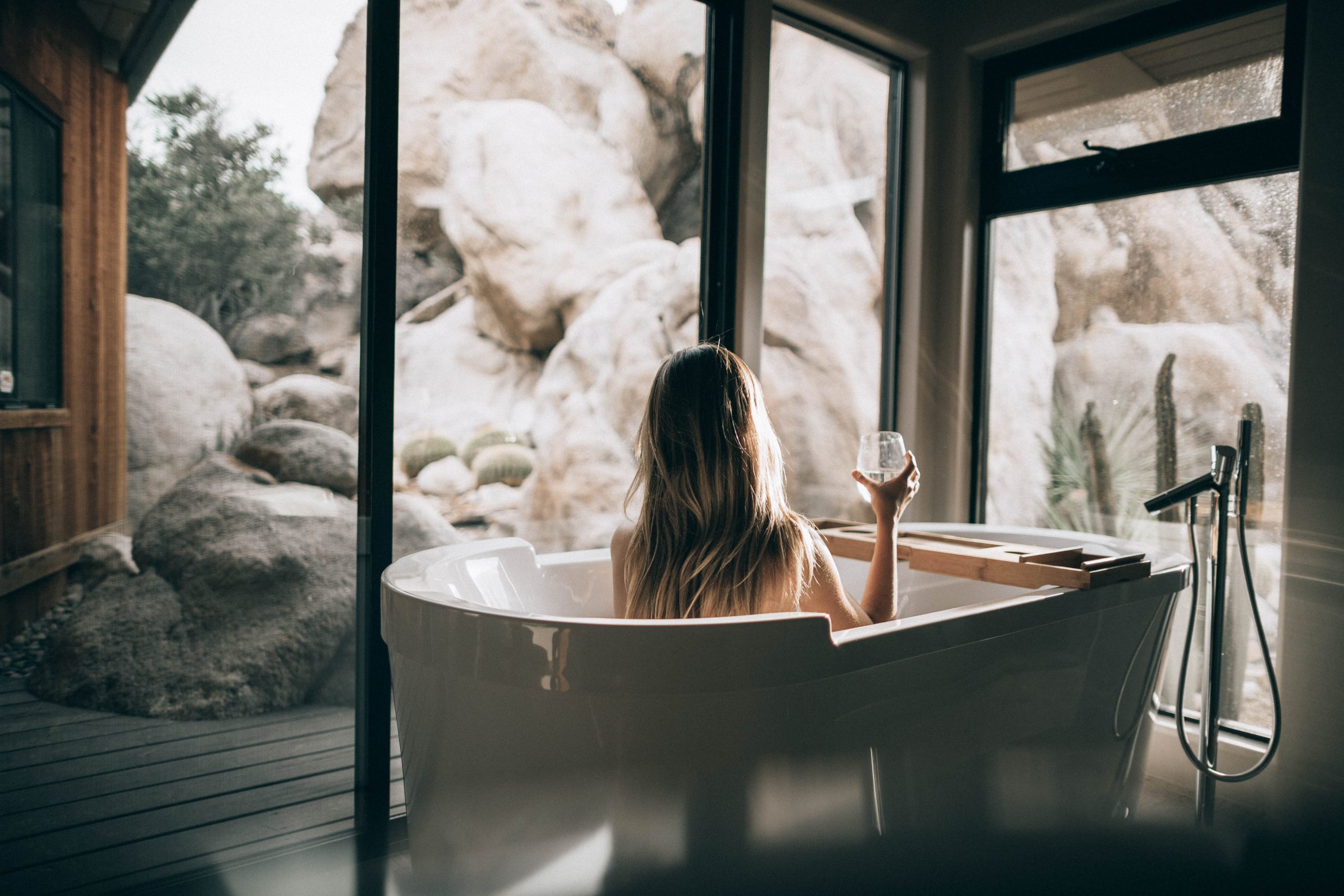Creating A Spa-Like Bathroom woman in white bathtub holding clear drinking glass