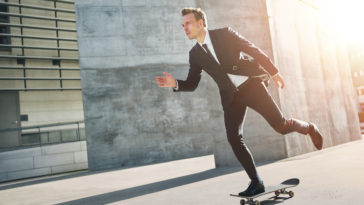 extremal man wearing suits rides a skateboard PGP664V