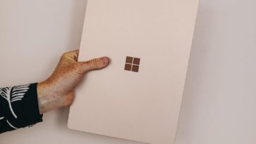 person holding sandstone microsoft surface laptop laptop