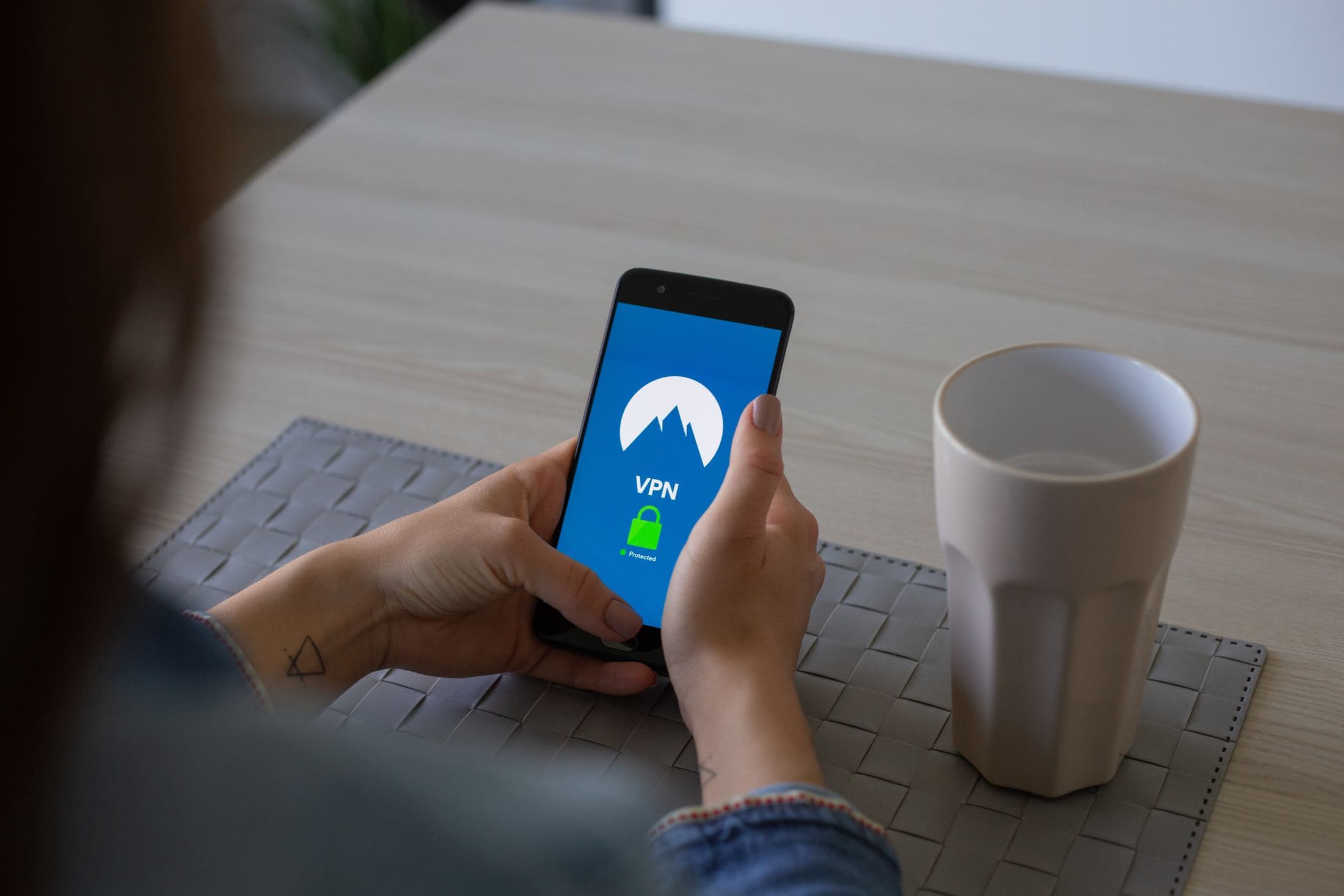 A Beginners Guide To Find Affordable Flight person holding black smartphone besides white cup