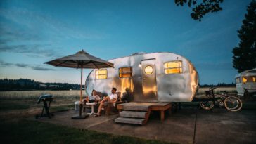 man and woman sitting in front of rv trailer