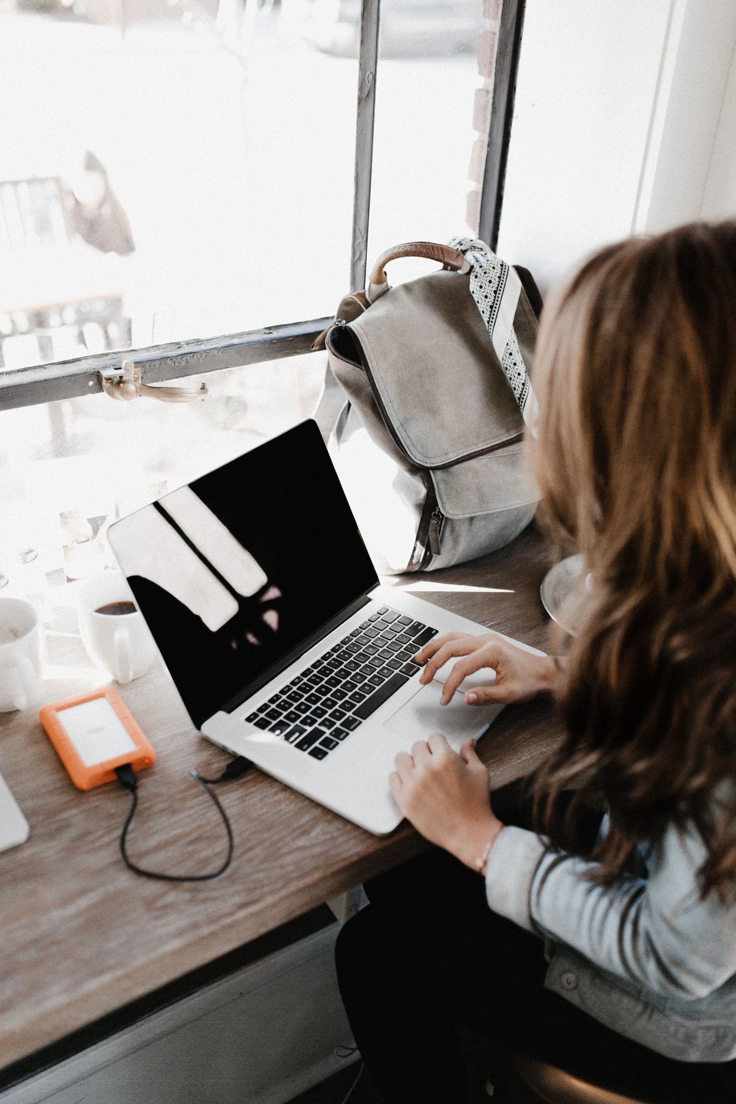How to Work on a Side Hustle with a Full-time Job girl wearing grey long-sleeved shirt using macbook pro on brown wooden table