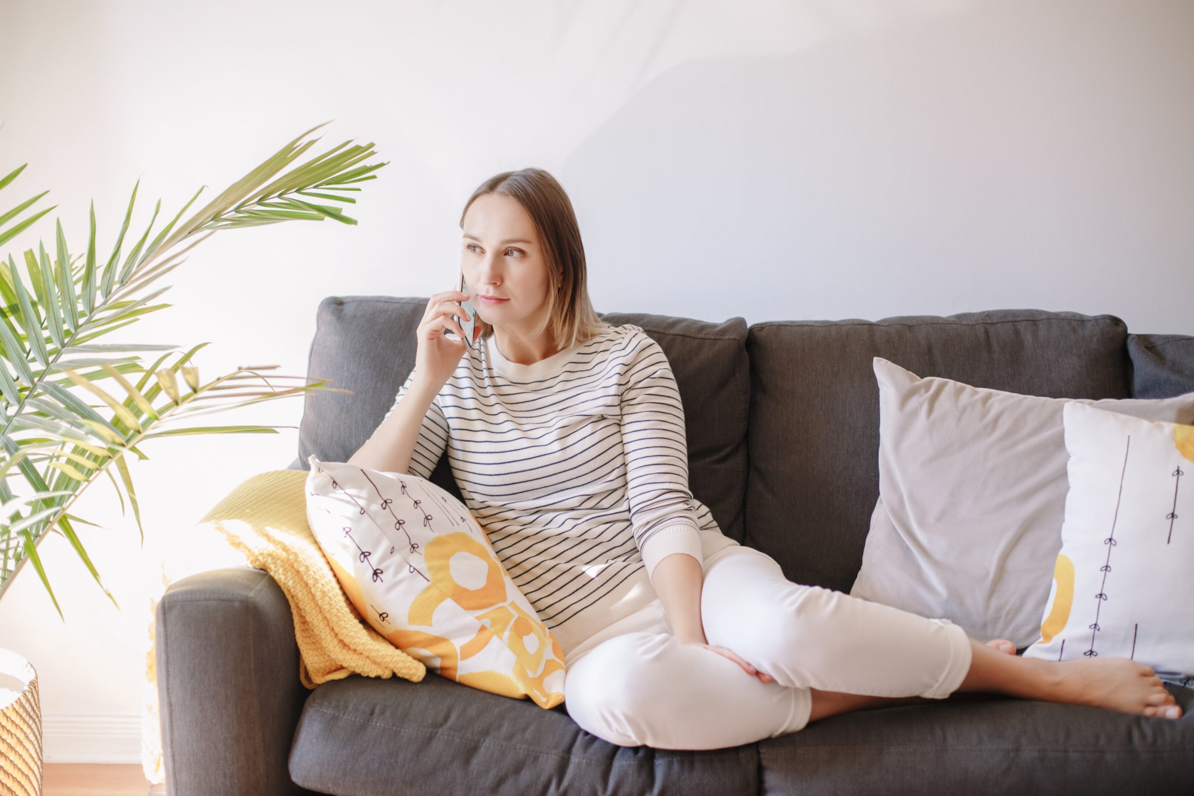 woman sitting on couch at home and talking on phon 6N4ZUKV