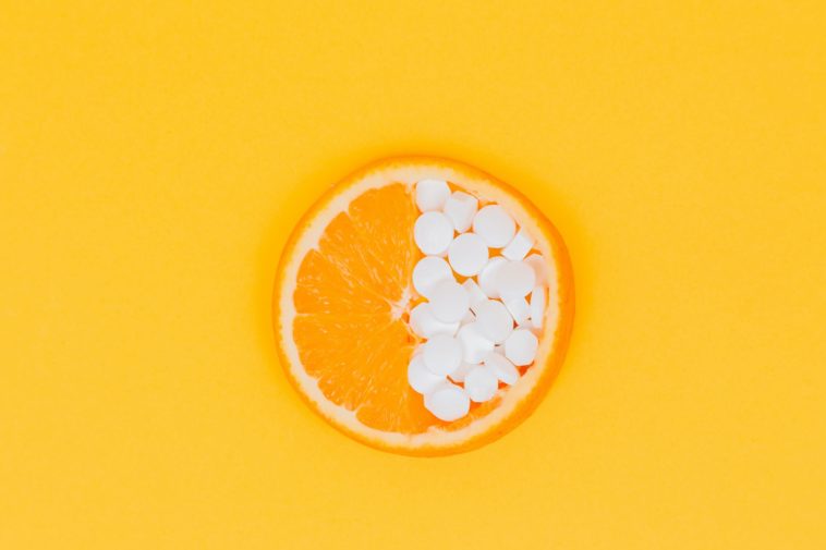 Vitamin C orange fruit slices on yellow surface