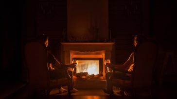 two people sitting in front of fireplace