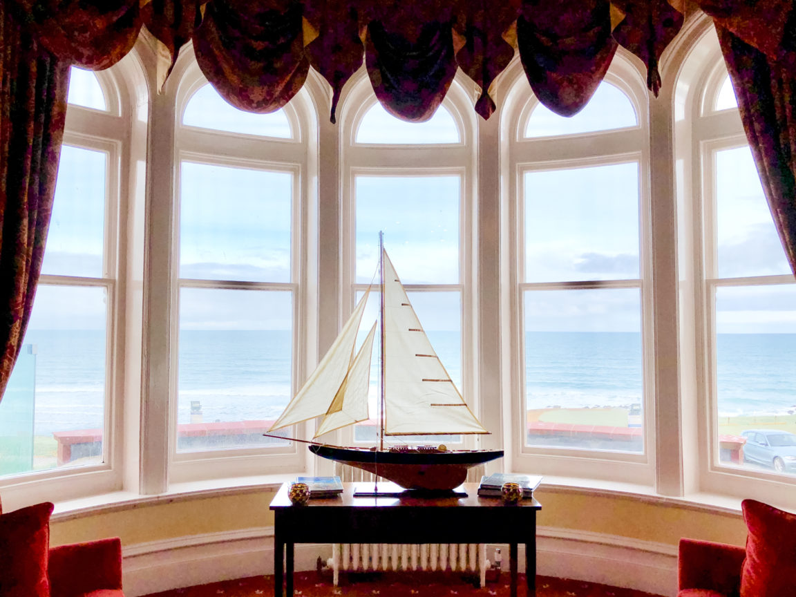 a model boat in a bay window looking out to sea 2021 08 29 04 42 40 utc