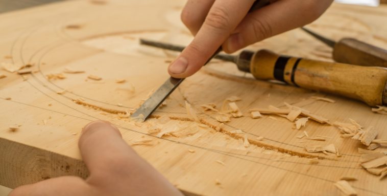 Carving person using chisel while curving wood