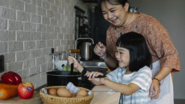 asian woman with granddaughter preparing food