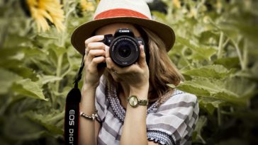 selective focus photography of woman holding dslr camera