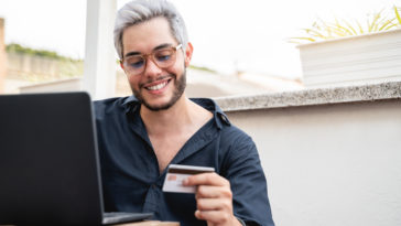 young hipster man holding credit cart using comput 2022 01 18 23 34 37 utc
