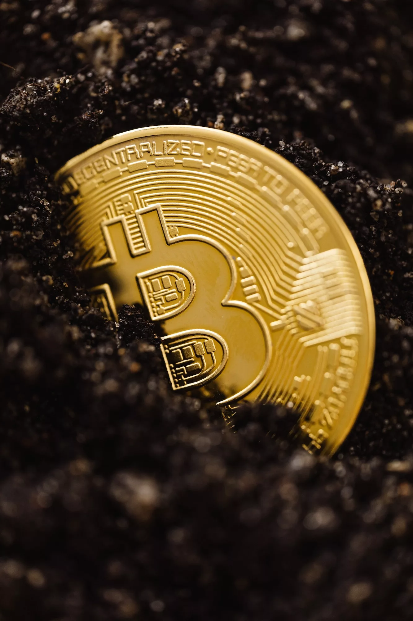 close-up shot of a bitcoin buried in the ground