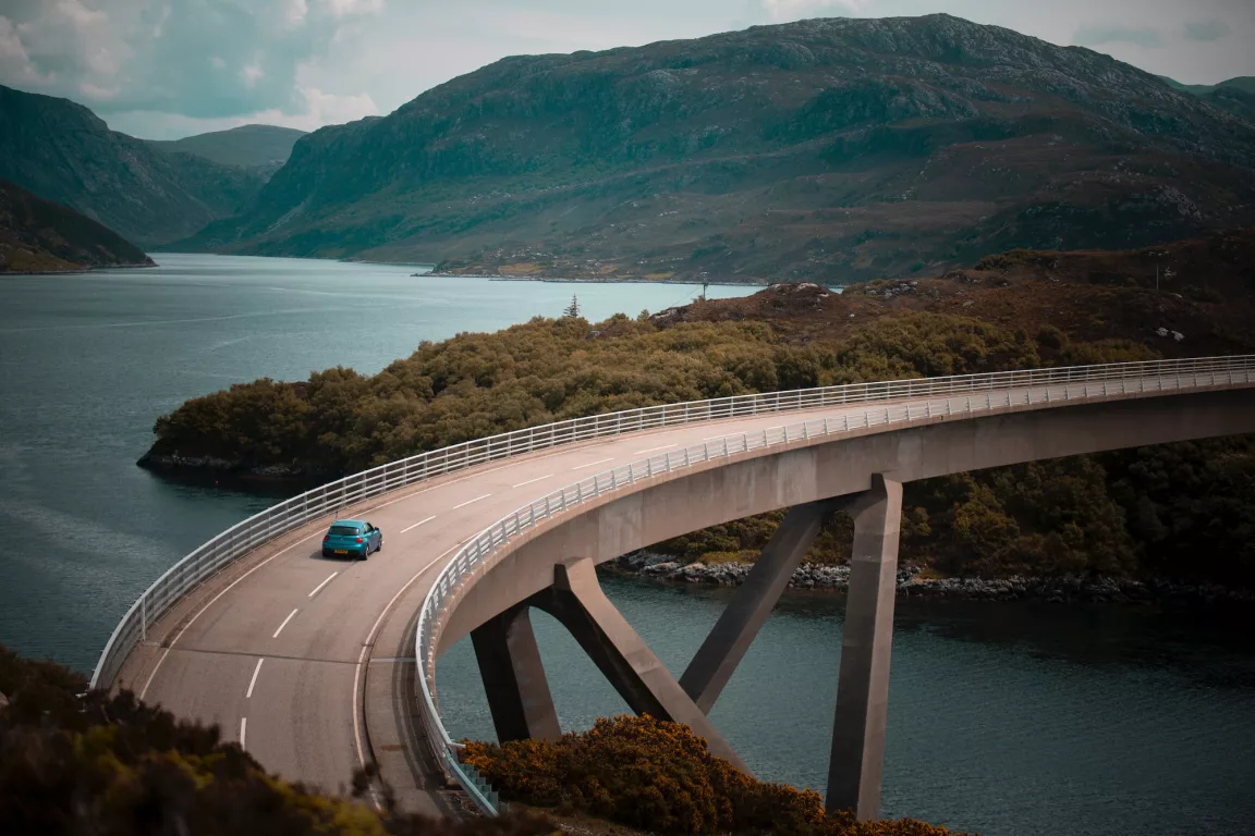 blue vehicle driving on bridge during daytime