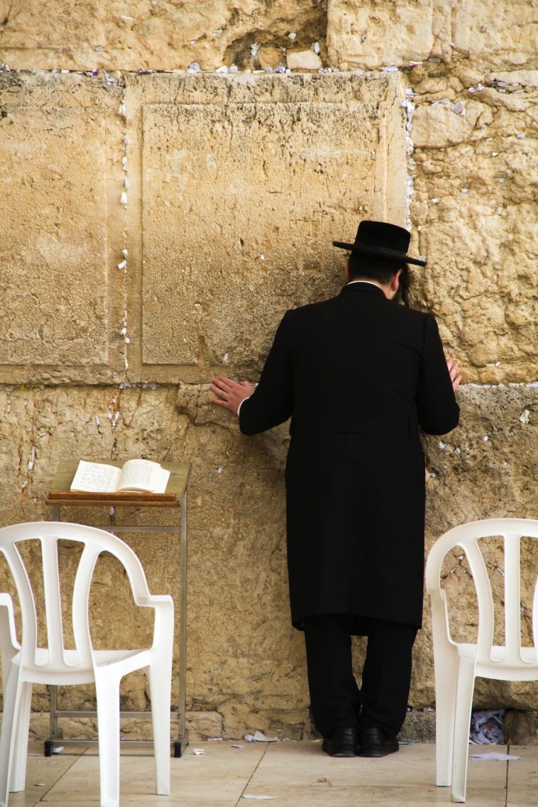 a person standing in front of a brick building with western wall in the background
