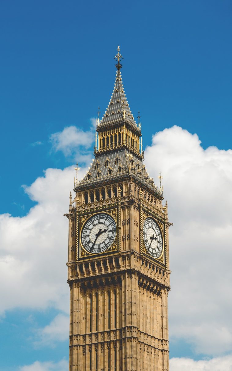 a large clock tower in front of a tall building with big ben in the background